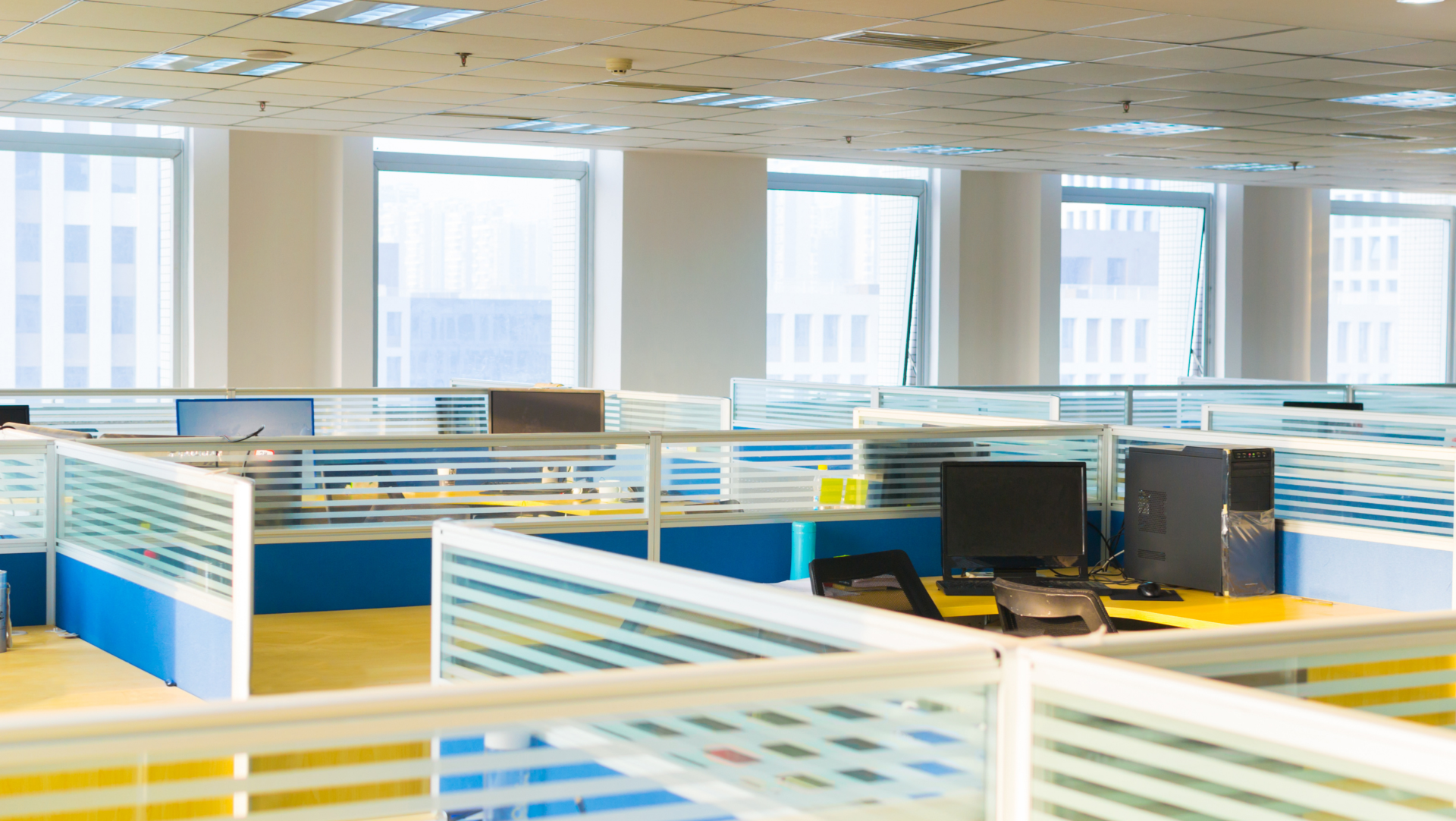 A large empty office with cubicles and a lot of windows.