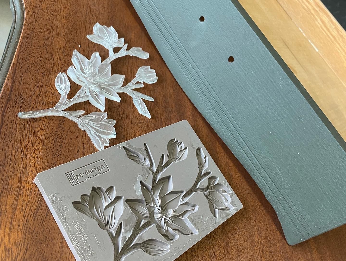 A piece of metal with flowers on it is on a wooden table