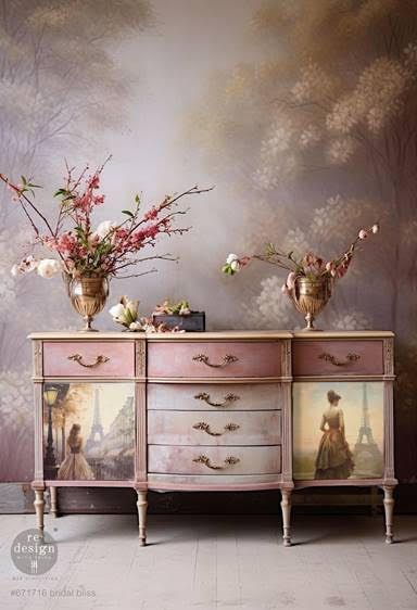 A pink dresser with two vases of flowers on top of it.