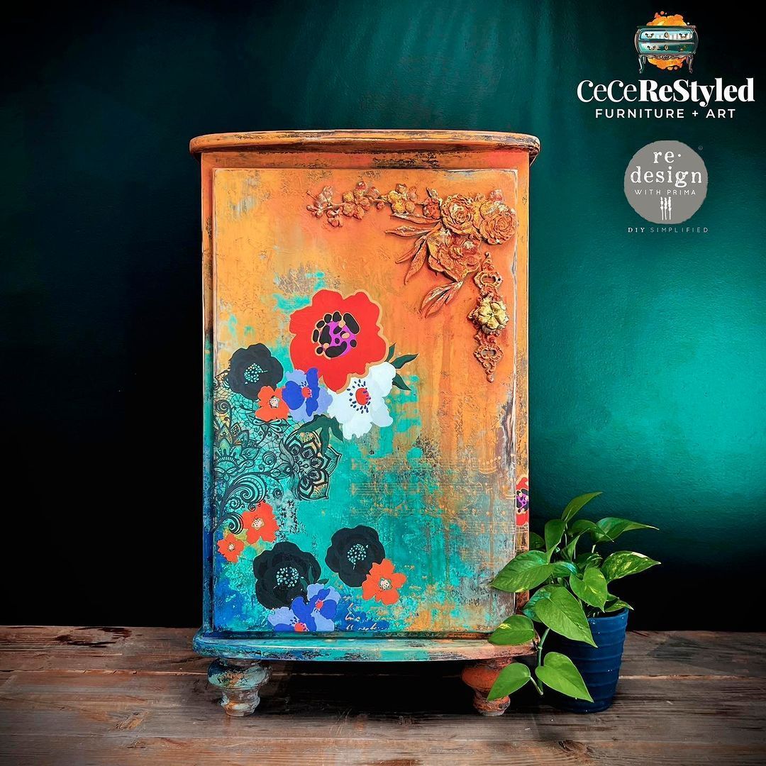 A wooden cabinet with flowers painted on it is sitting on a wooden table.