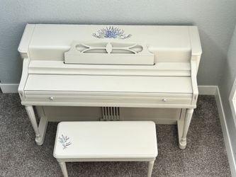 A white piano with a bench underneath it