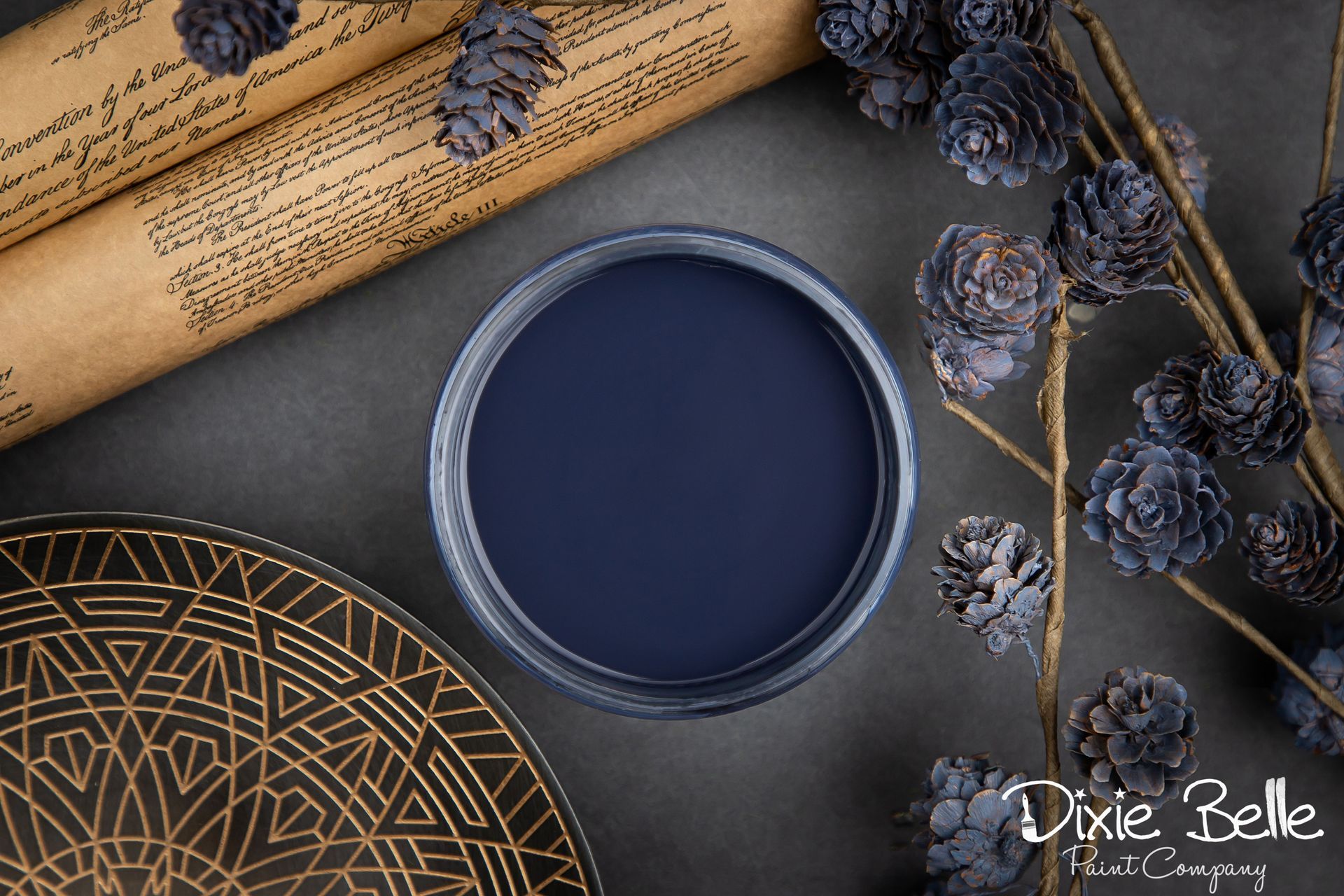A bowl of blue paint is sitting on a table next to flowers.