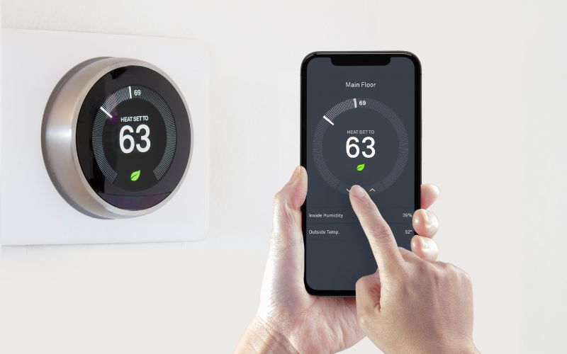 A person is using a smart phone to control a thermostat.