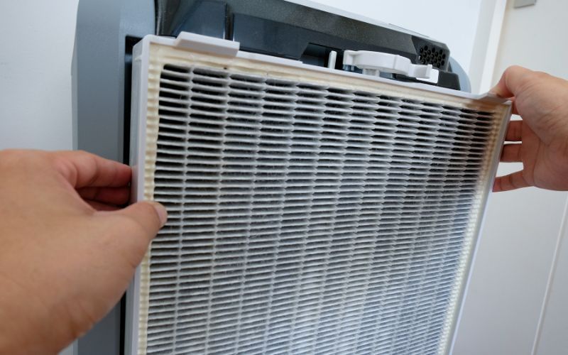 A person is changing a filter on an air purifier.