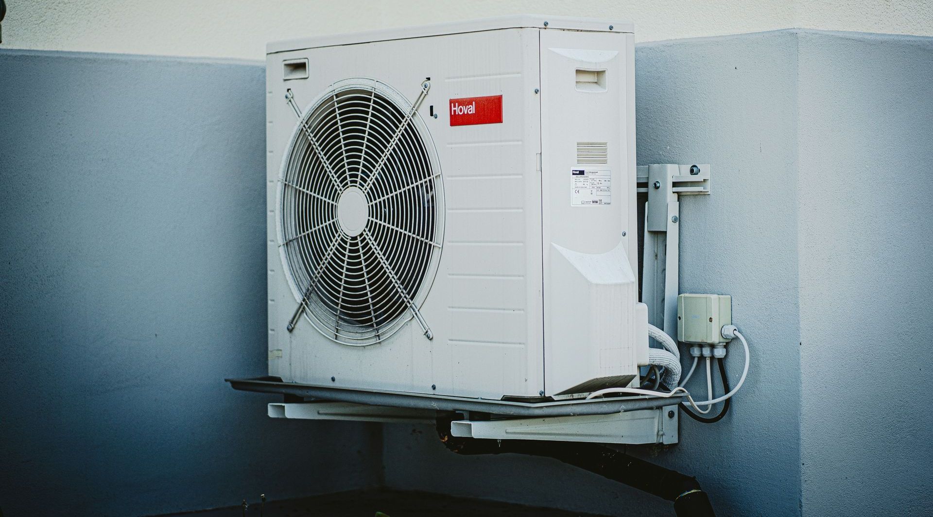 A white air conditioner is mounted to the side of a building.