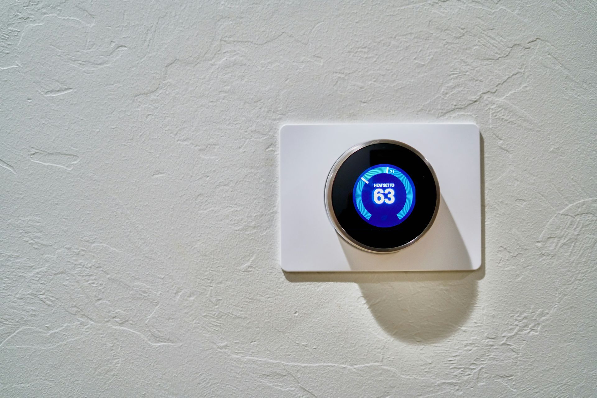 A smart thermostat is sitting on a white wall.