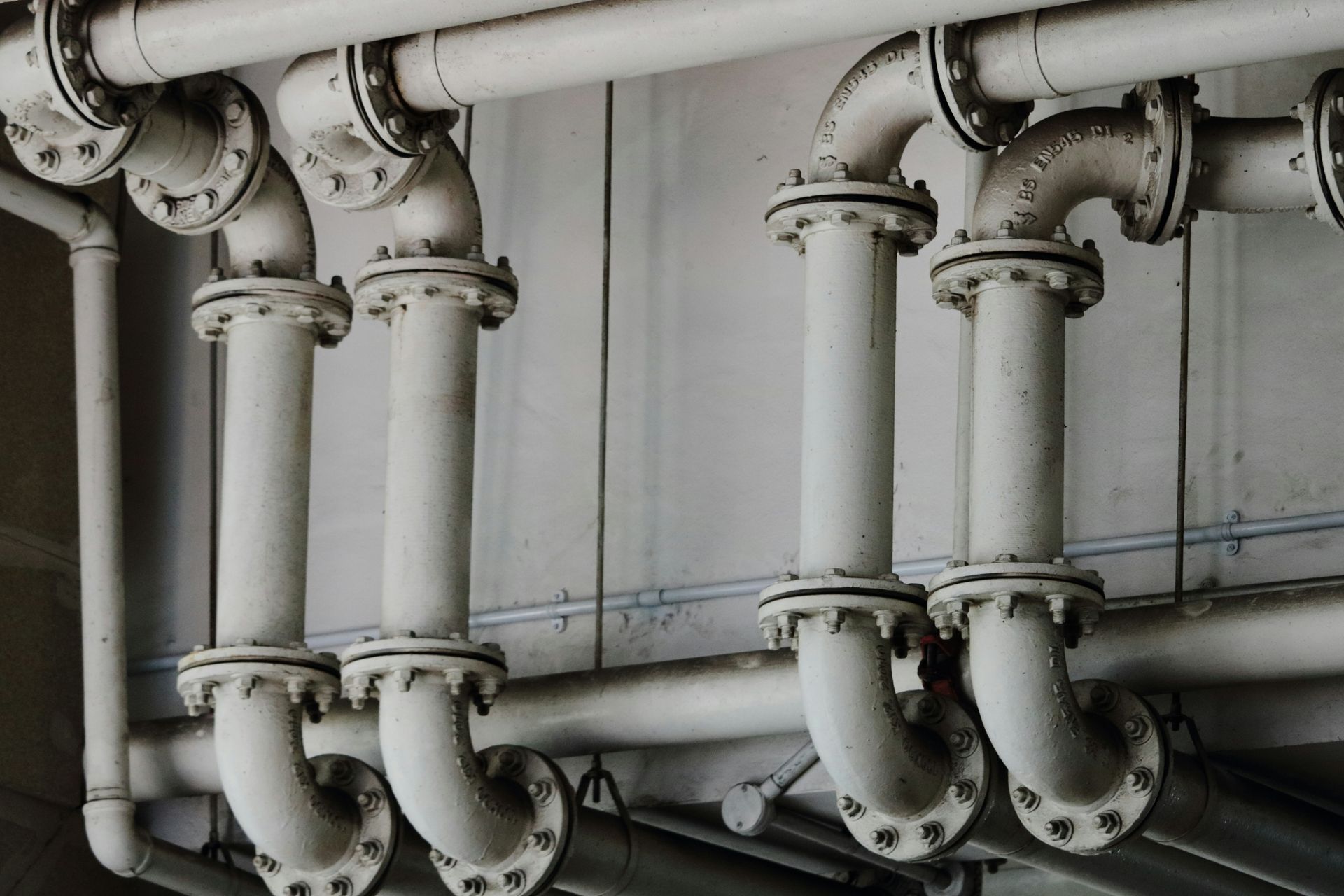 A row of white pipes hanging from the ceiling of a building.