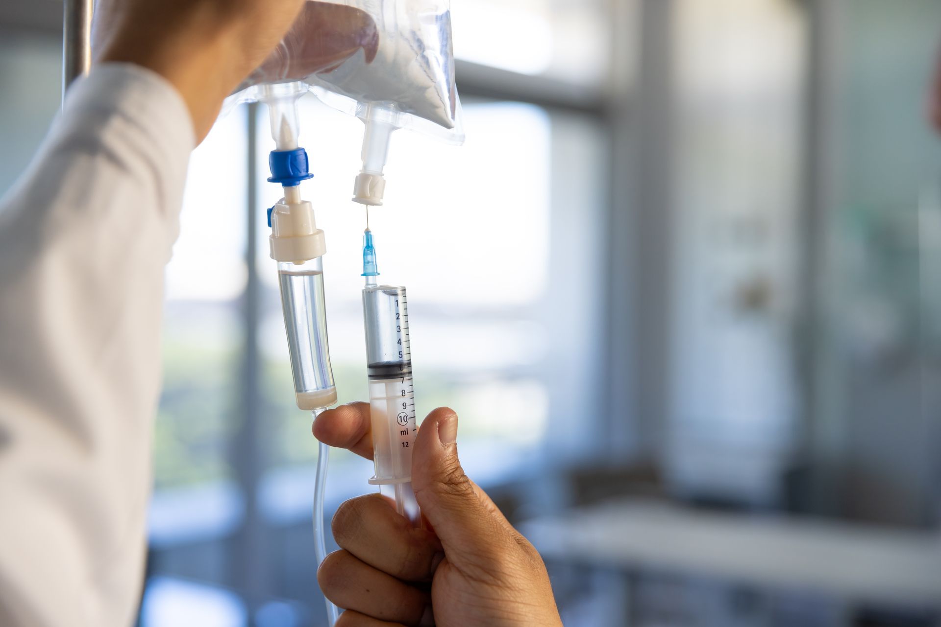 A person is holding a syringe and an iv bag.