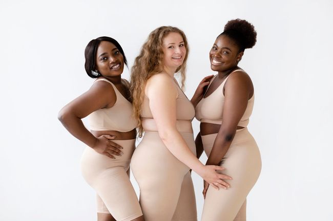 Three plus size women are posing for a picture together.