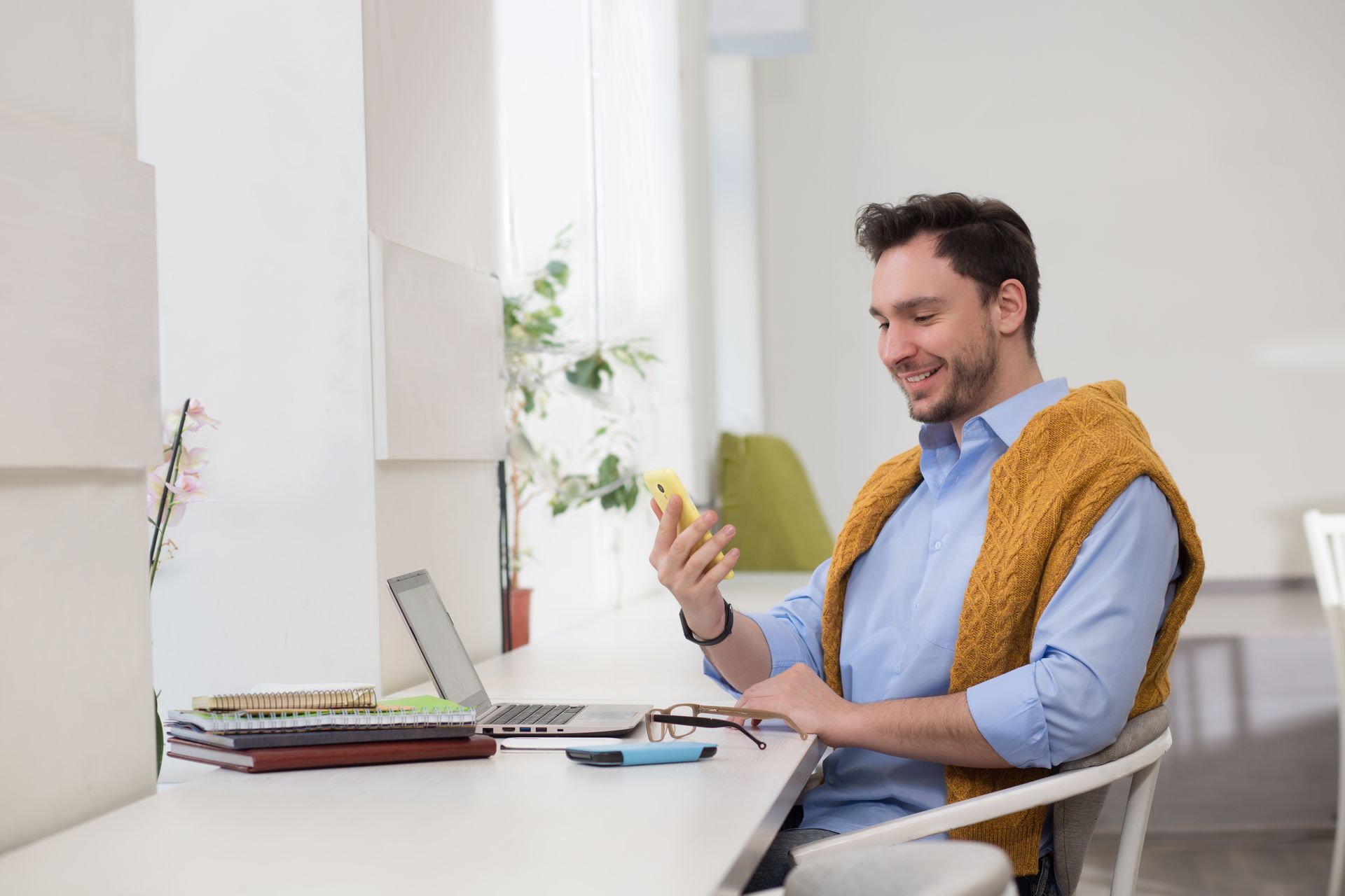 A man is sitting at a desk looking at his cell phone.