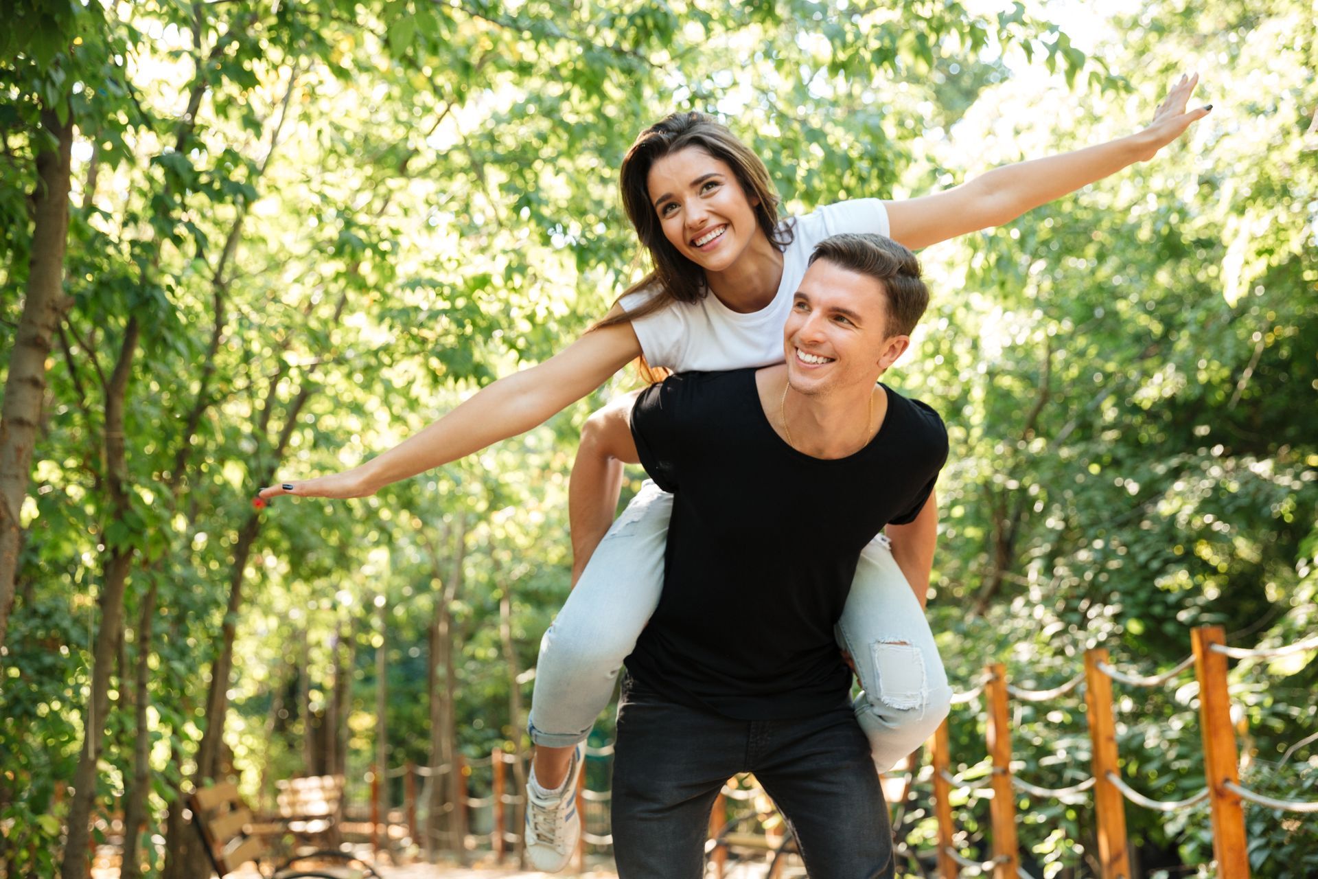 A man is carrying a woman on his back in a park.