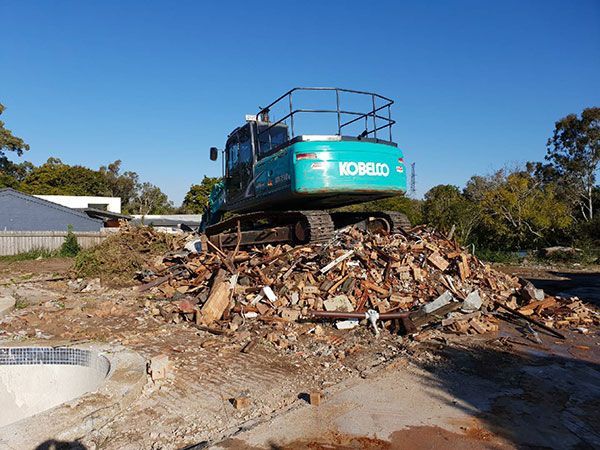 Two construction vehicles are parked next to each other on a dirt road.