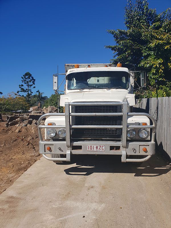 Two construction vehicles are parked next to each other on a dirt road.