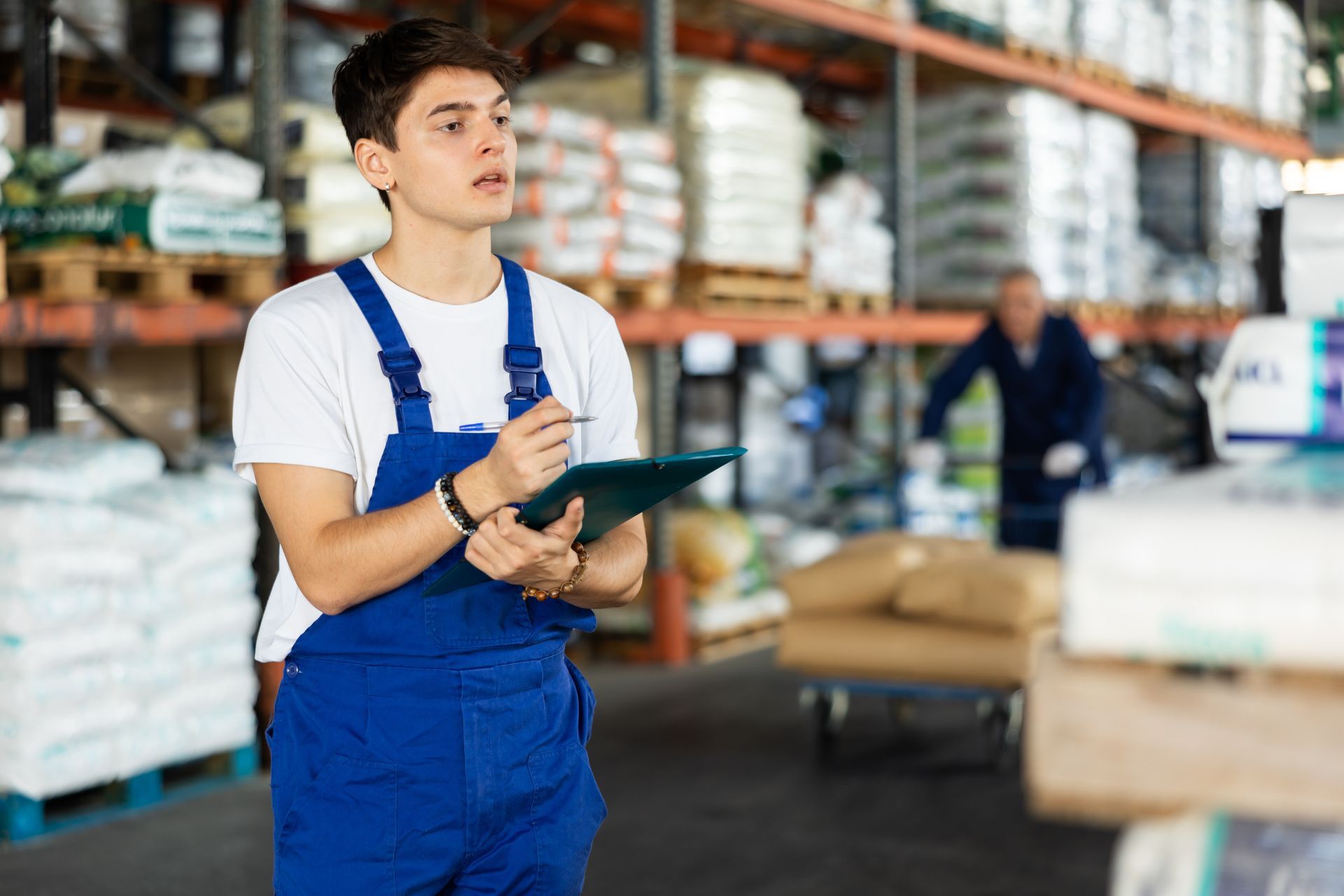 An employee conducts an inventory of soil goods in a warehouse while using a clipboard.