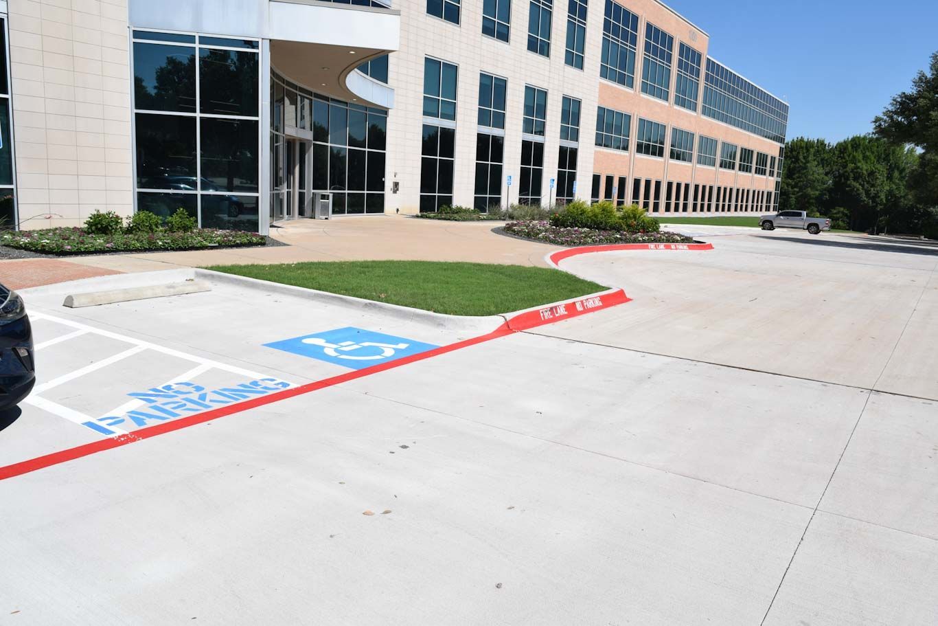 Exterior view of a building with a handicapped parking space marked with blue paint and a wheelchair symbol on the concrete pavement.