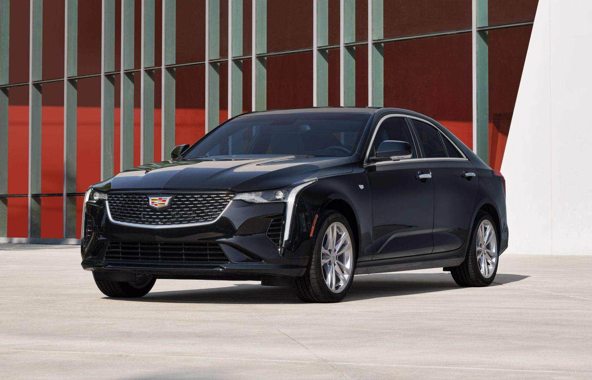 A black cadillac is parked in front of a building.