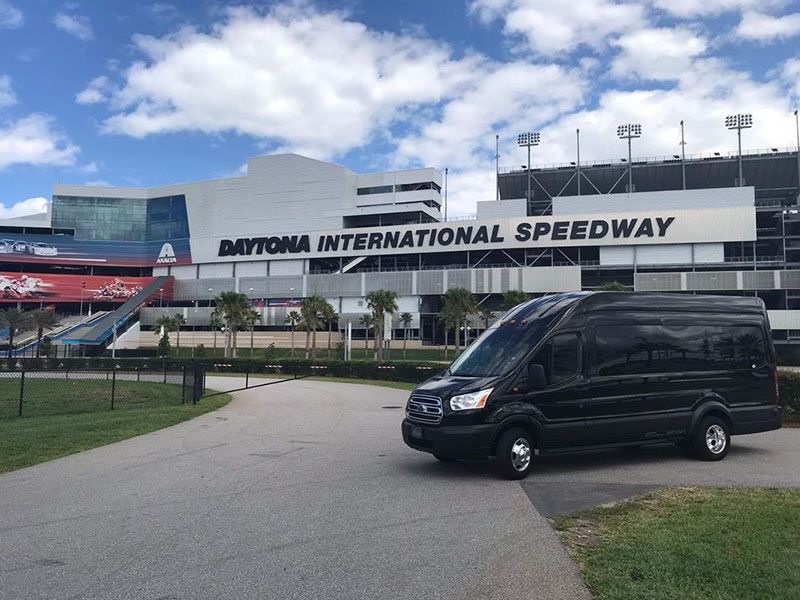 A black van is parked in front of the daytona international speedway.