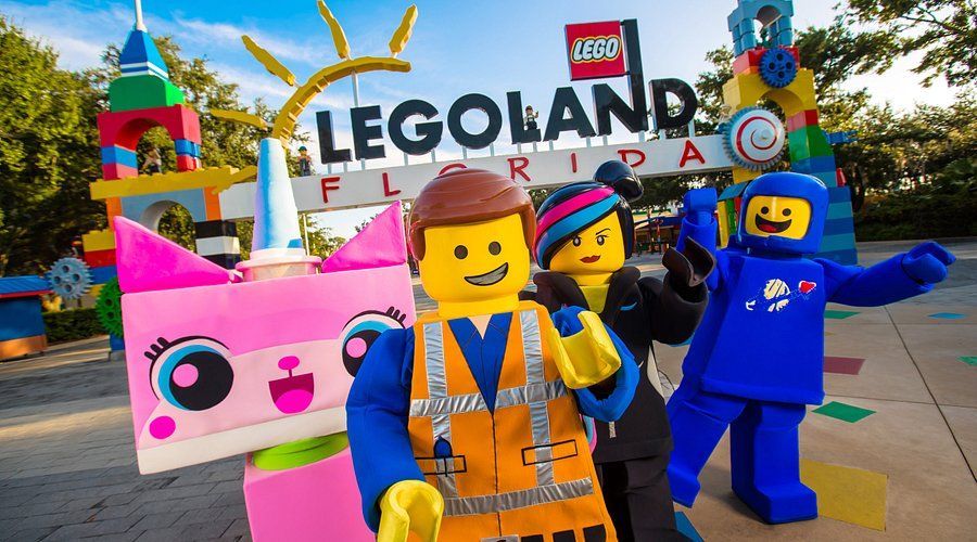 A group of lego characters are standing in front of a legoland sign.