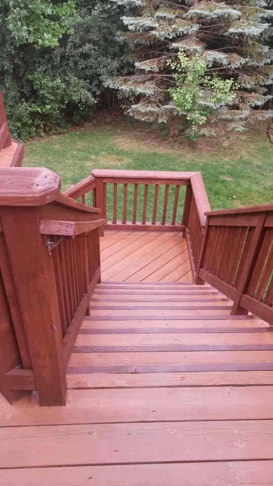 Wooden deck stairs descending to a grassy yard with trees and a small landing.