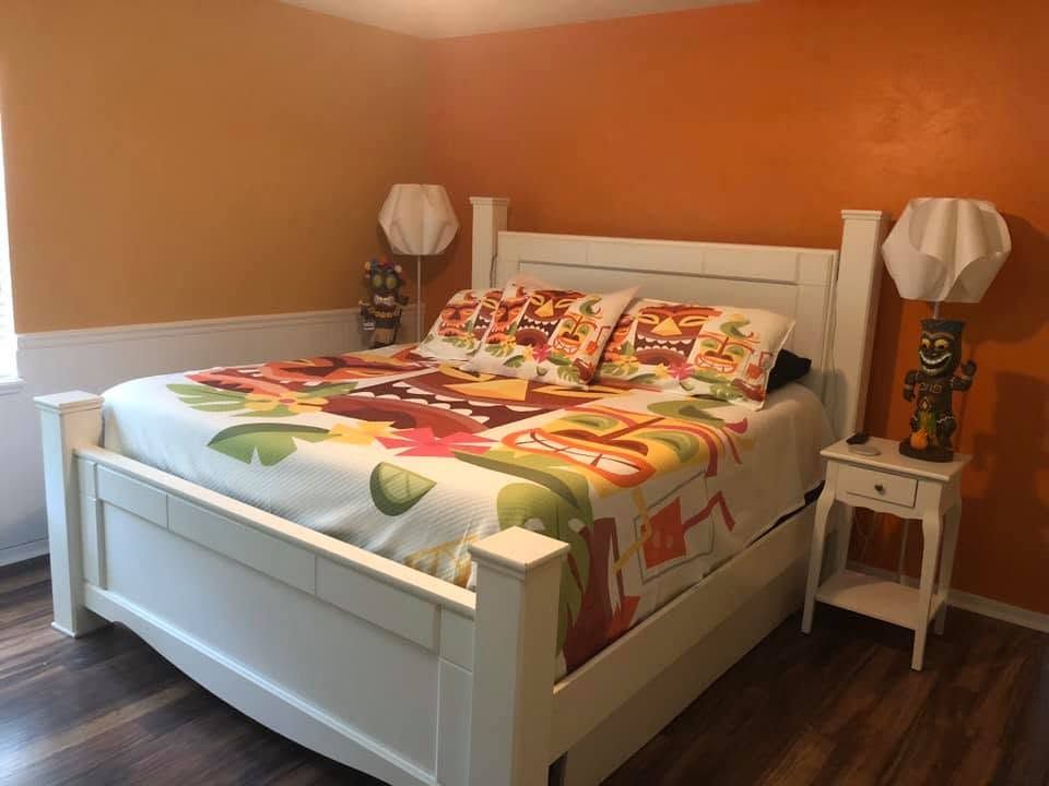 Bedroom with white bed, colorful bedding, orange walls, and matching bedside lamps