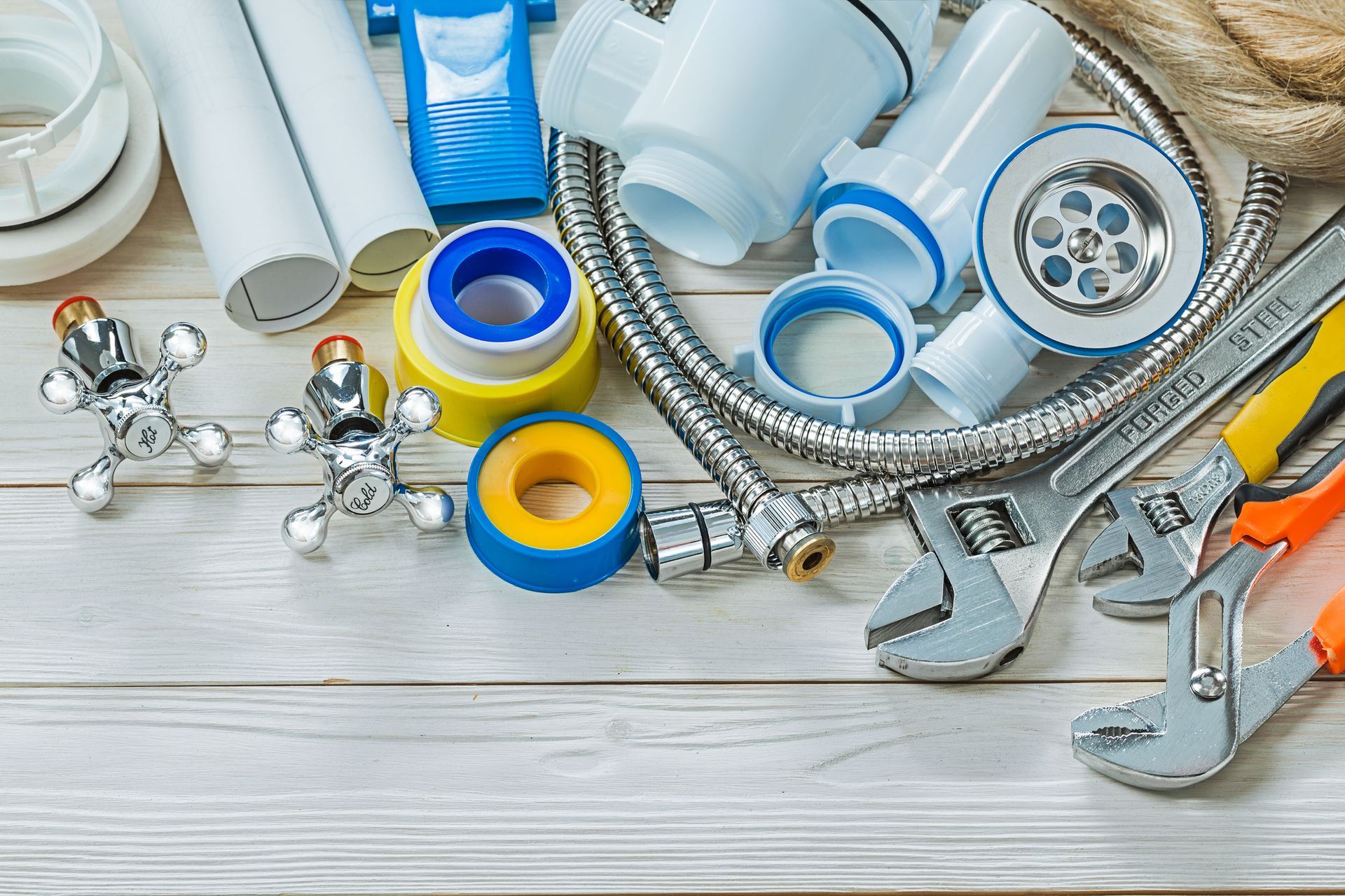 A bunch of plumbing tools are on a wooden table.