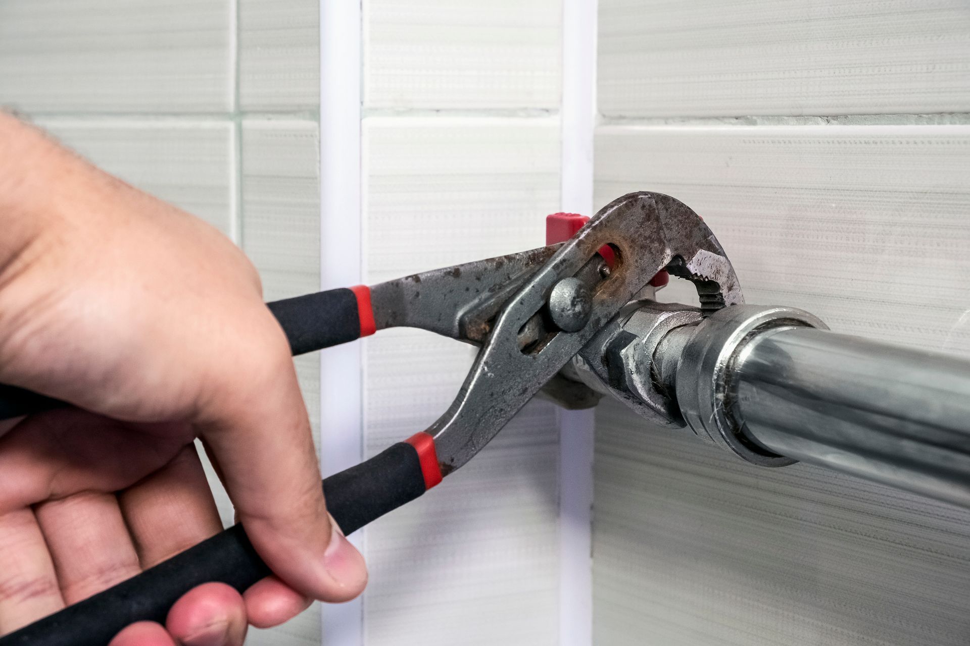 A person is fixing a pipe with a wrench.