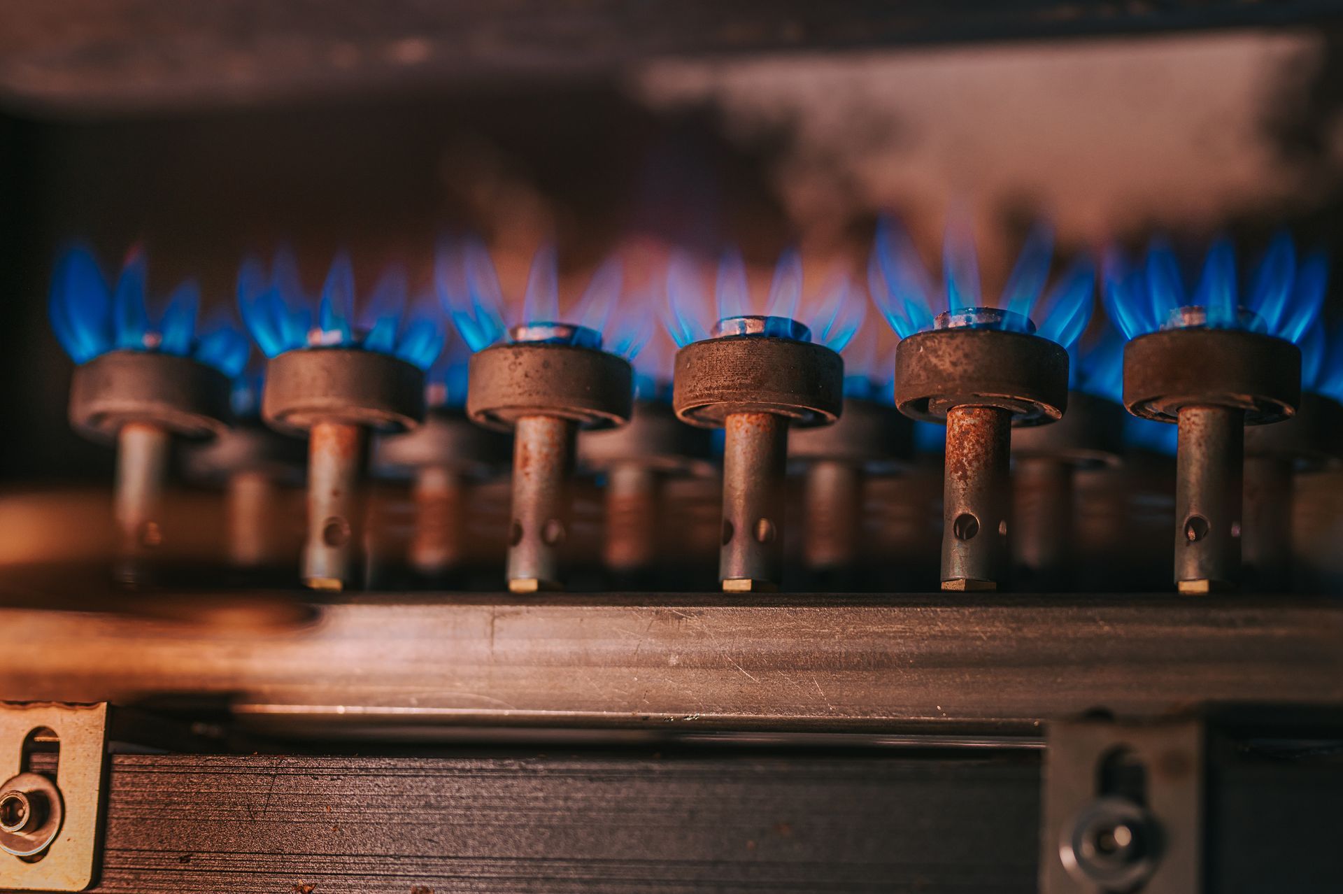 A close up of a gas burner with blue flames coming out of it.