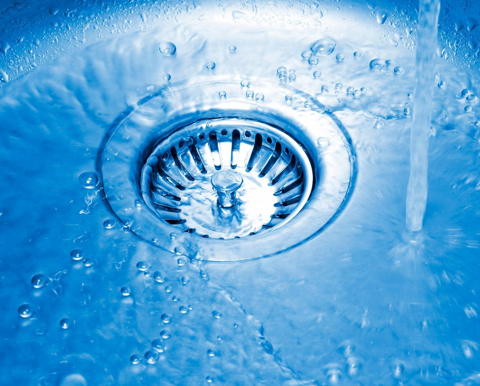 A close up of a sink drain with water coming out of it