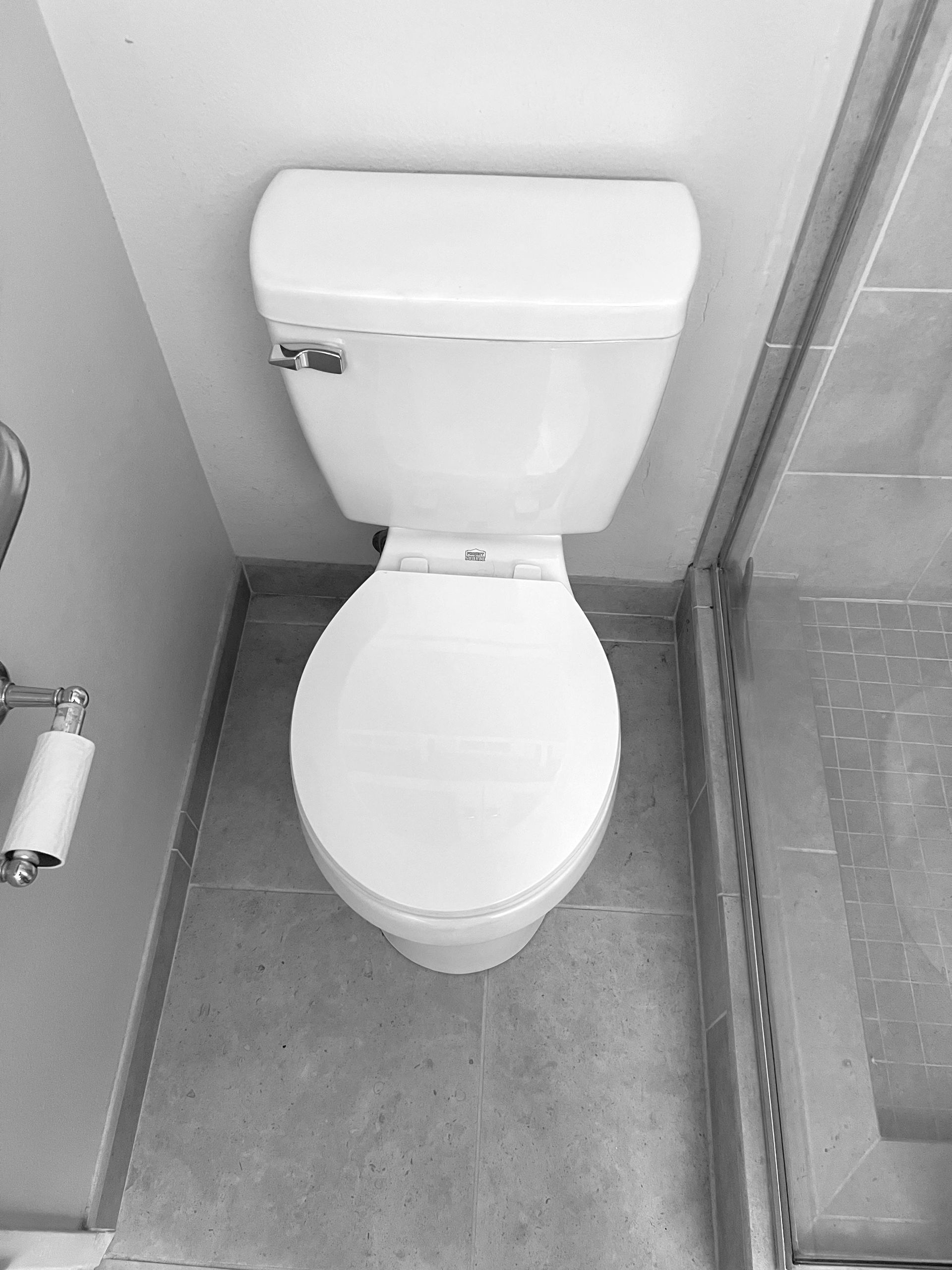A black and white photo of a toilet in a bathroom.