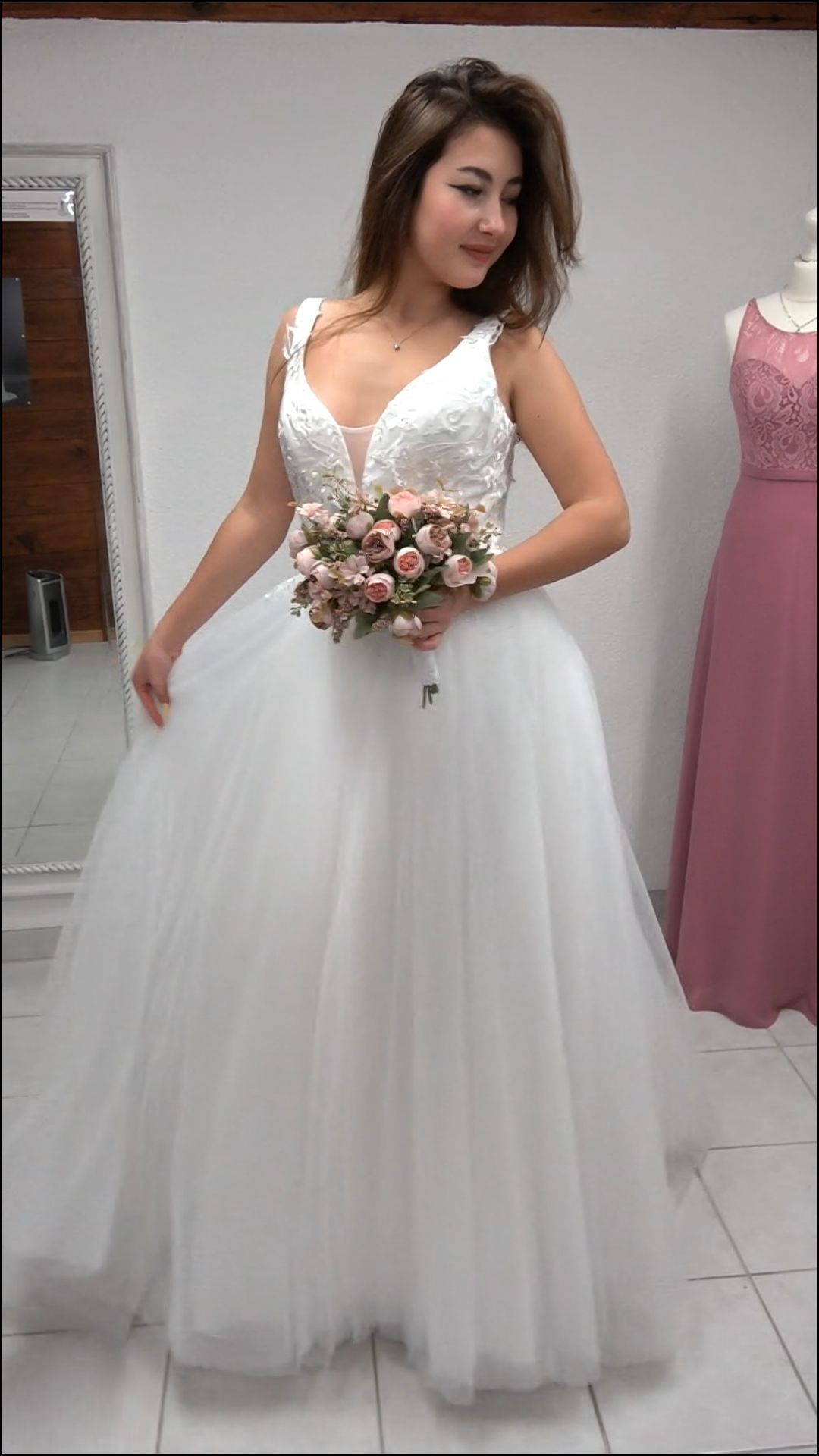 Eine Frau in einem weißen Brautkleid hält einen Blumenstrauß.