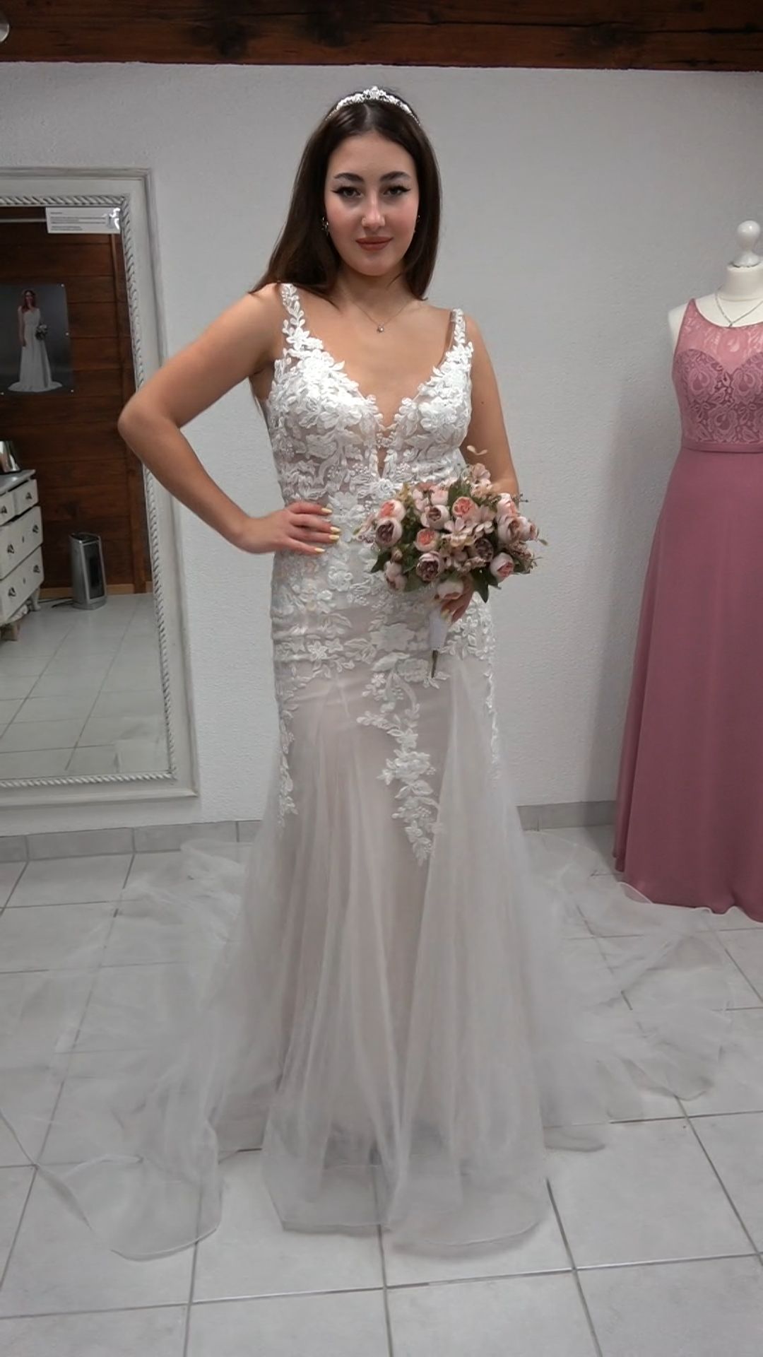 Eine Frau in einem Brautkleid hält einen Blumenstrauß.