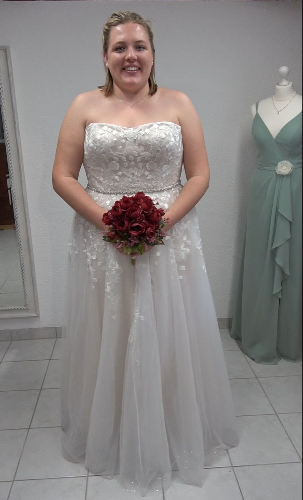 Eine Frau in einem Brautkleid hält einen Blumenstrauß.