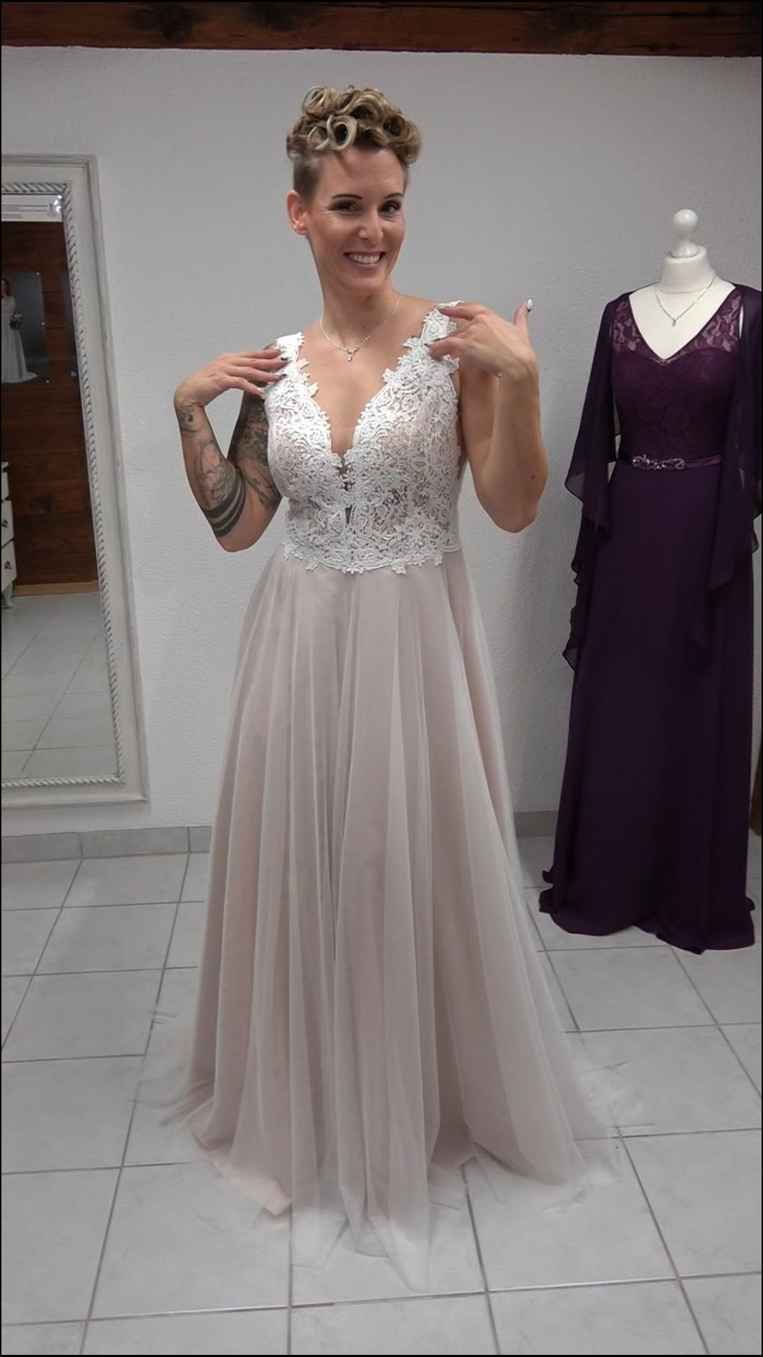 Eine Frau in einem Brautkleid steht vor einer Schaufensterpuppe.