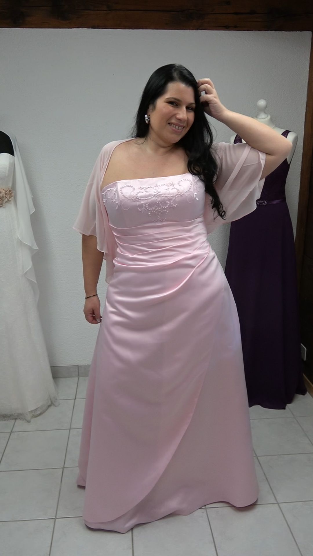 Eine Frau in einem rosa Kleid steht in einem Raum.