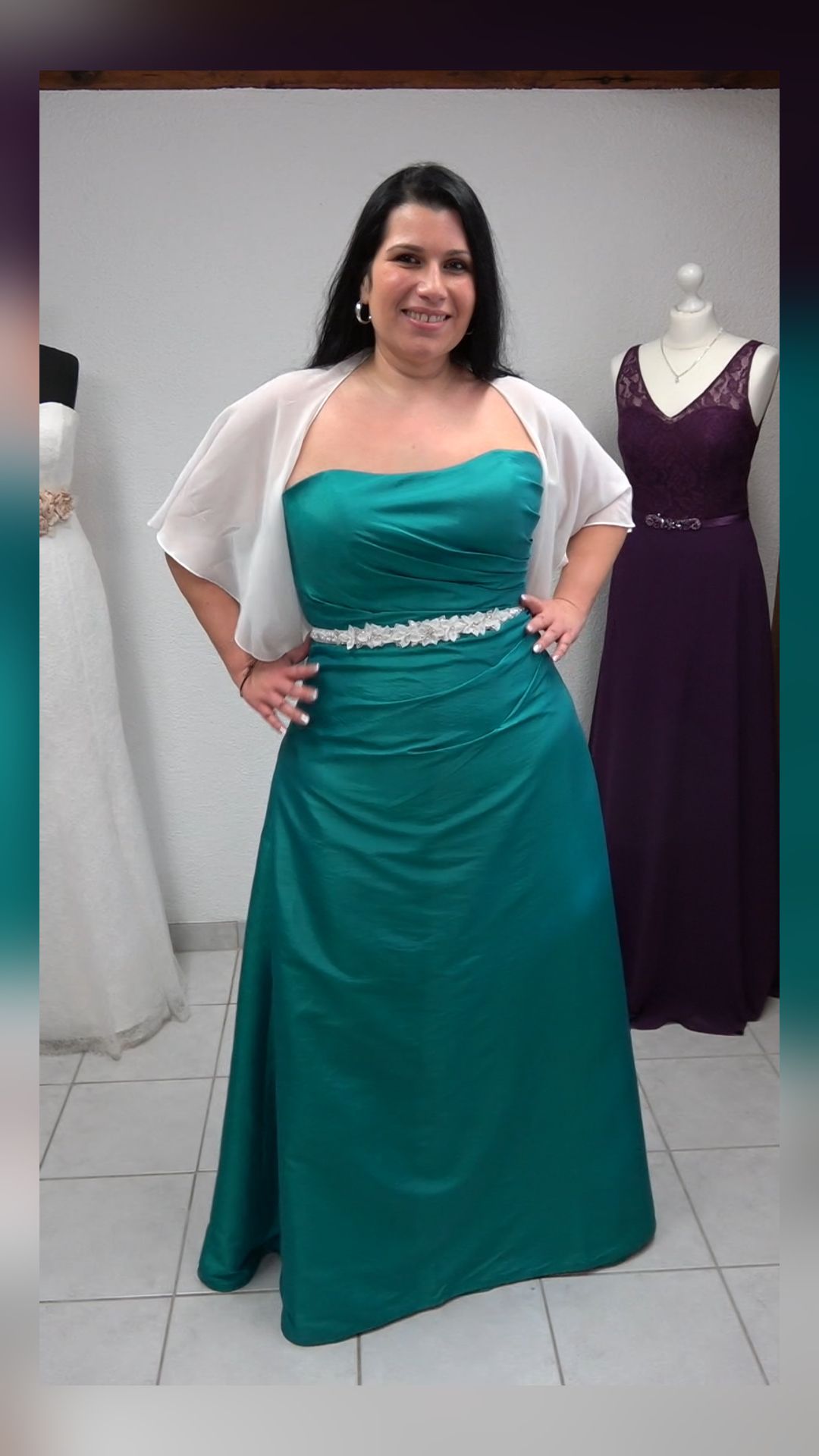 Eine Frau trägt ein grünes Kleid und eine weiße Jacke.