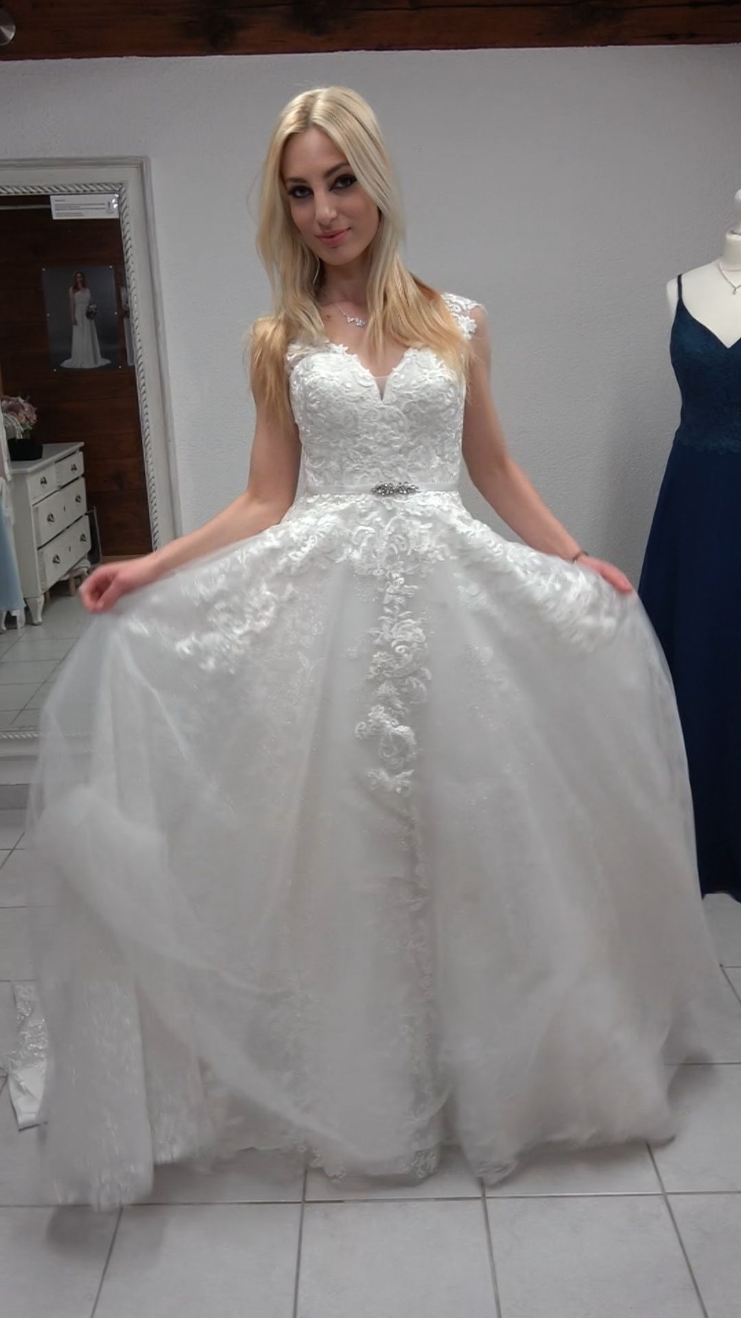 Eine Frau in einem weißen Brautkleid steht in einem Raum.