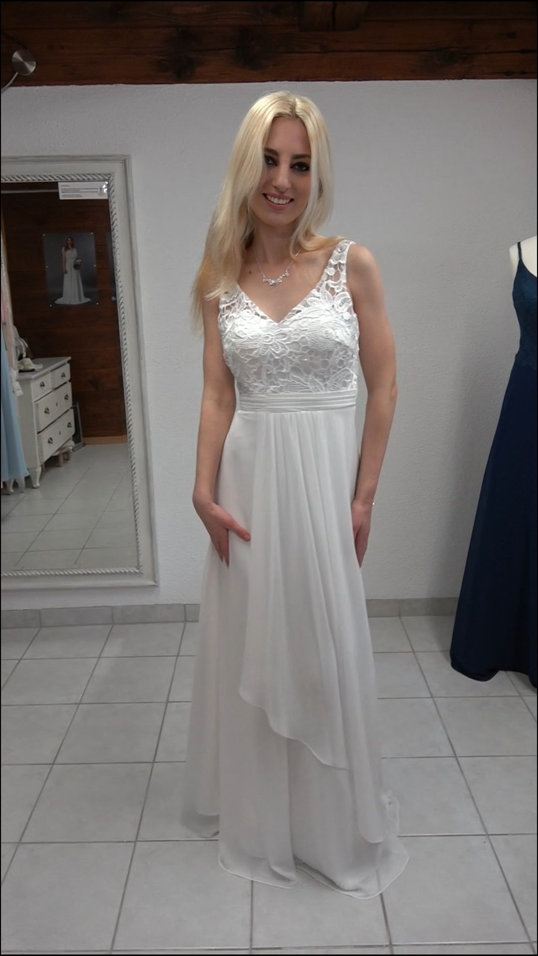 Eine Frau in einem weißen Kleid steht vor einem Spiegel.