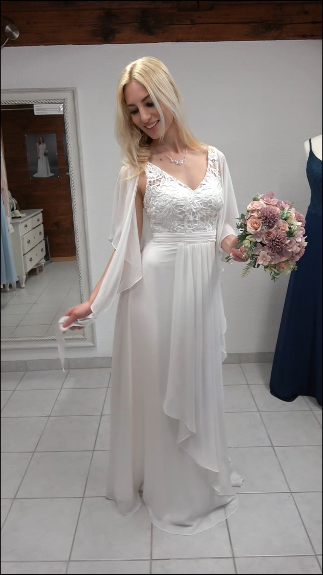 Eine Frau in einem weißen Brautkleid hält einen Blumenstrauß.