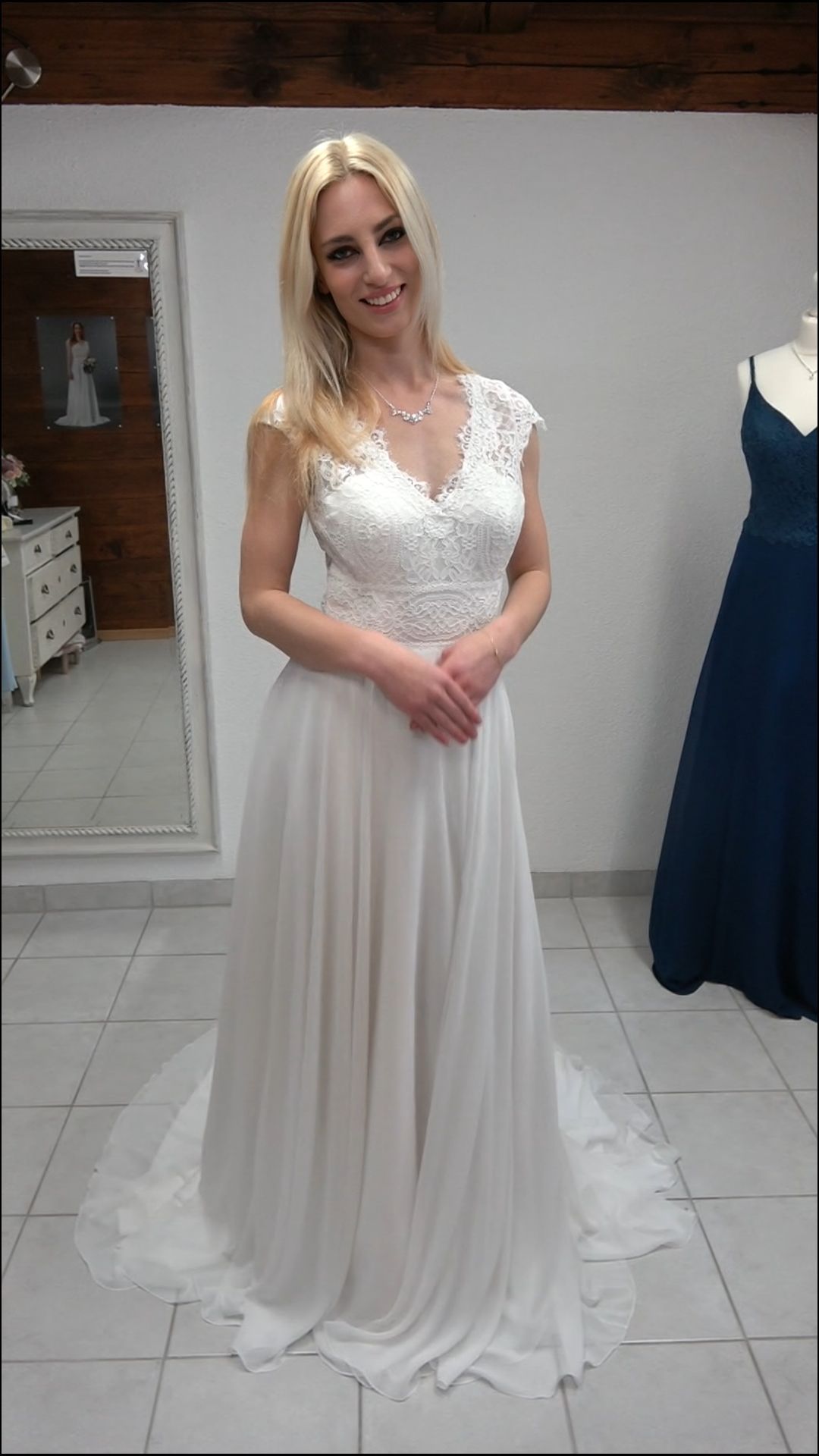 Eine Frau in einem weißen Brautkleid steht vor einem Spiegel.