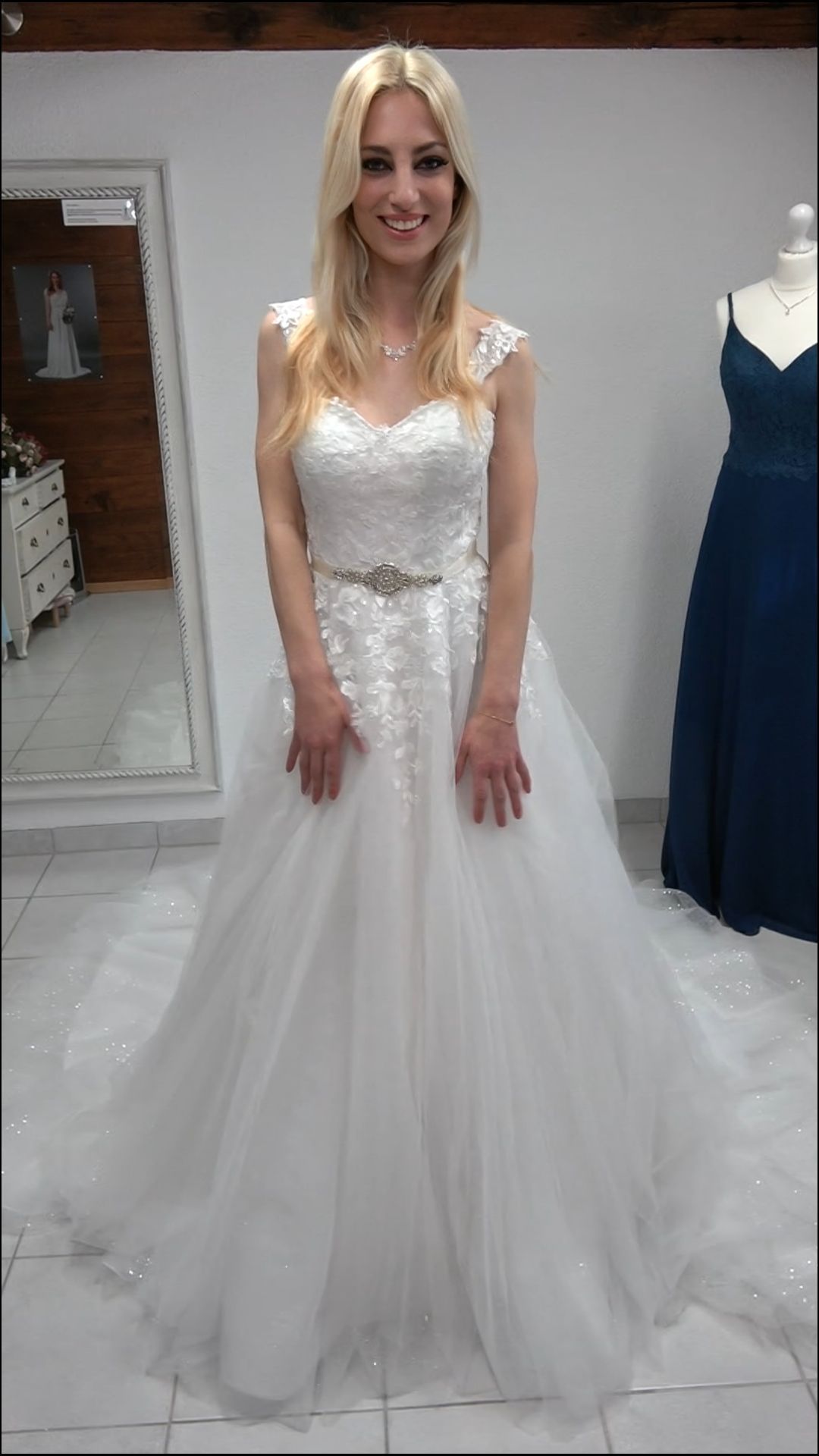 Eine Frau in einem weißen Brautkleid steht vor einem Spiegel.