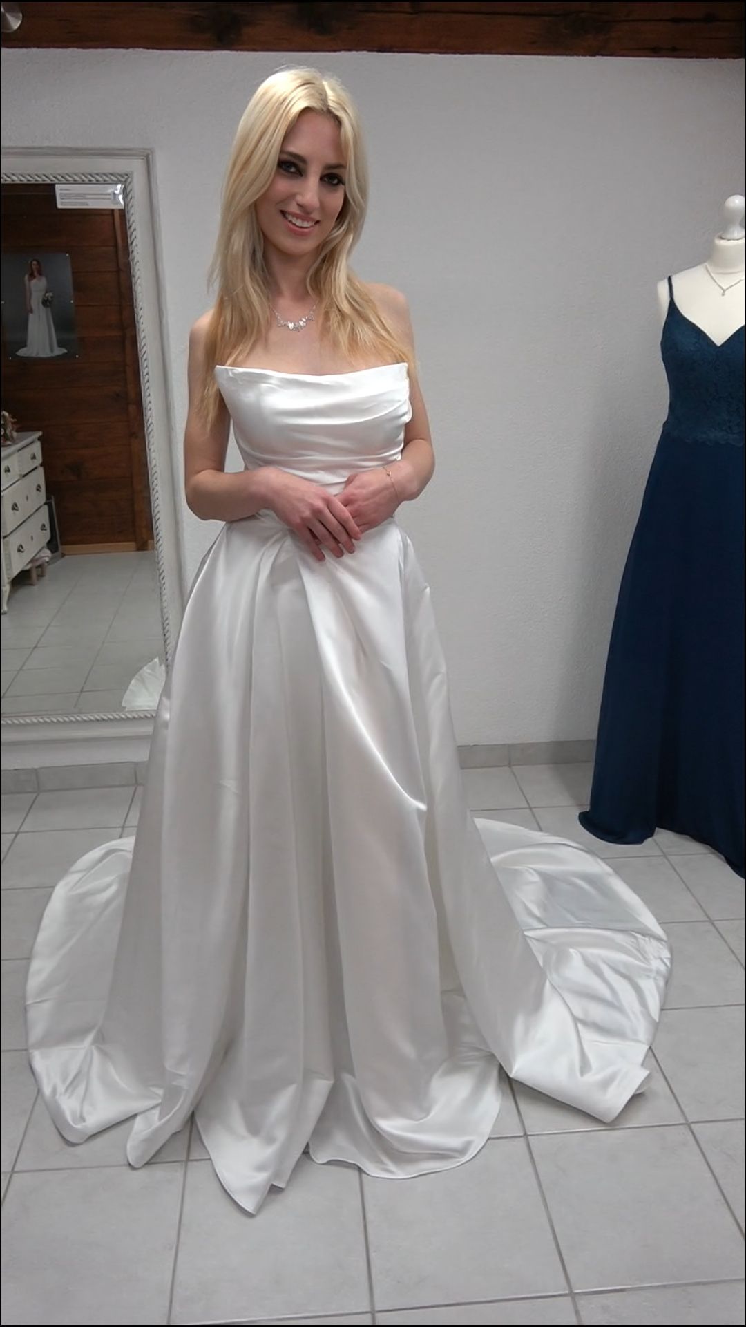 Eine Frau in einem weißen Brautkleid steht vor einem Spiegel.