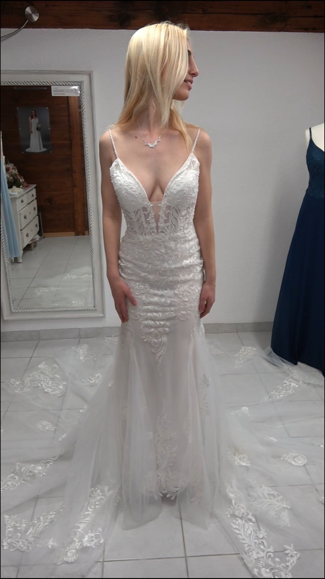 Eine Frau in einem Brautkleid steht in einem Zimmer vor einem Spiegel.