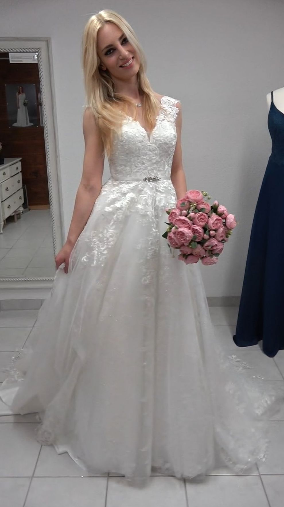 Eine Frau in einem Brautkleid hält einen Blumenstrauß.