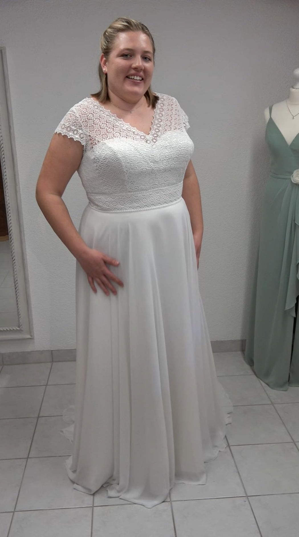 Eine Frau in einem weißen Brautkleid steht in einem Raum.