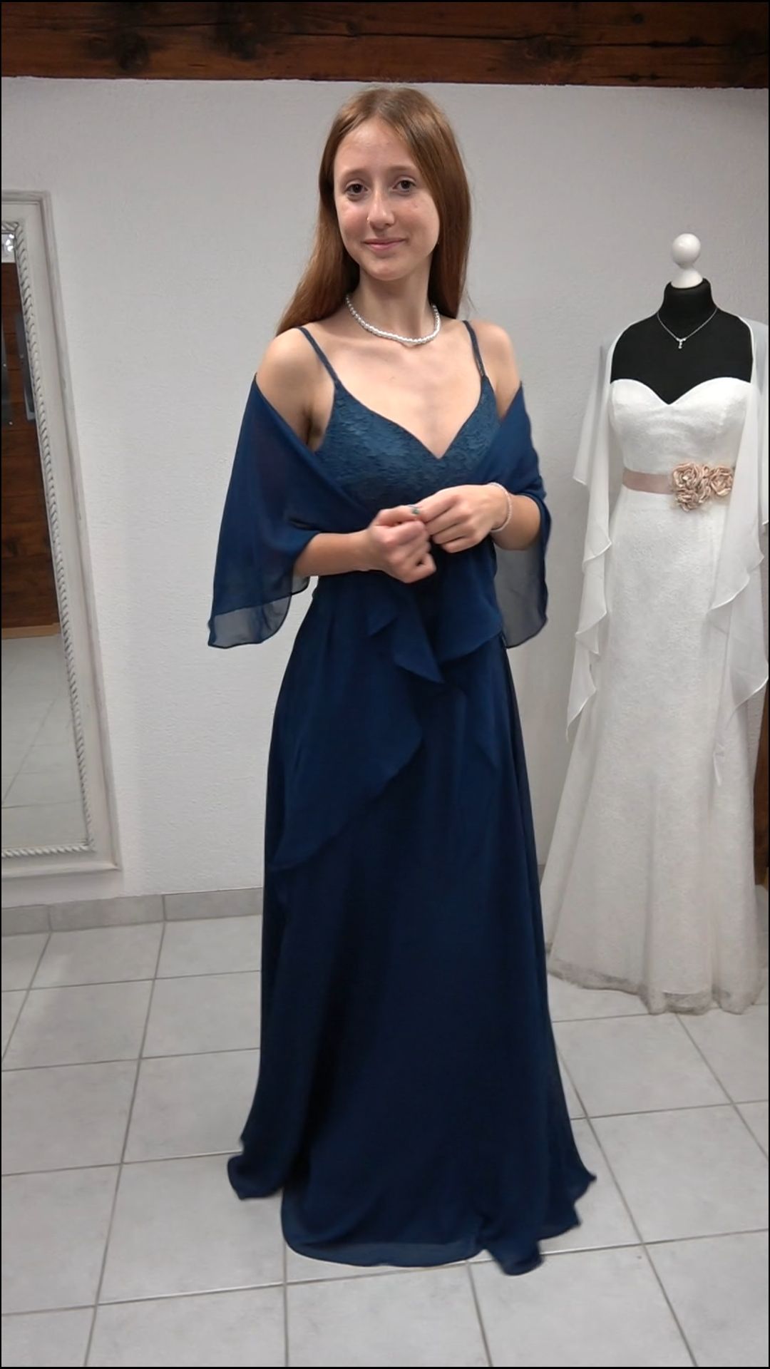 Eine Frau in einem blauen Kleid steht vor einer Schaufensterpuppe, die ein weißes Kleid trägt.