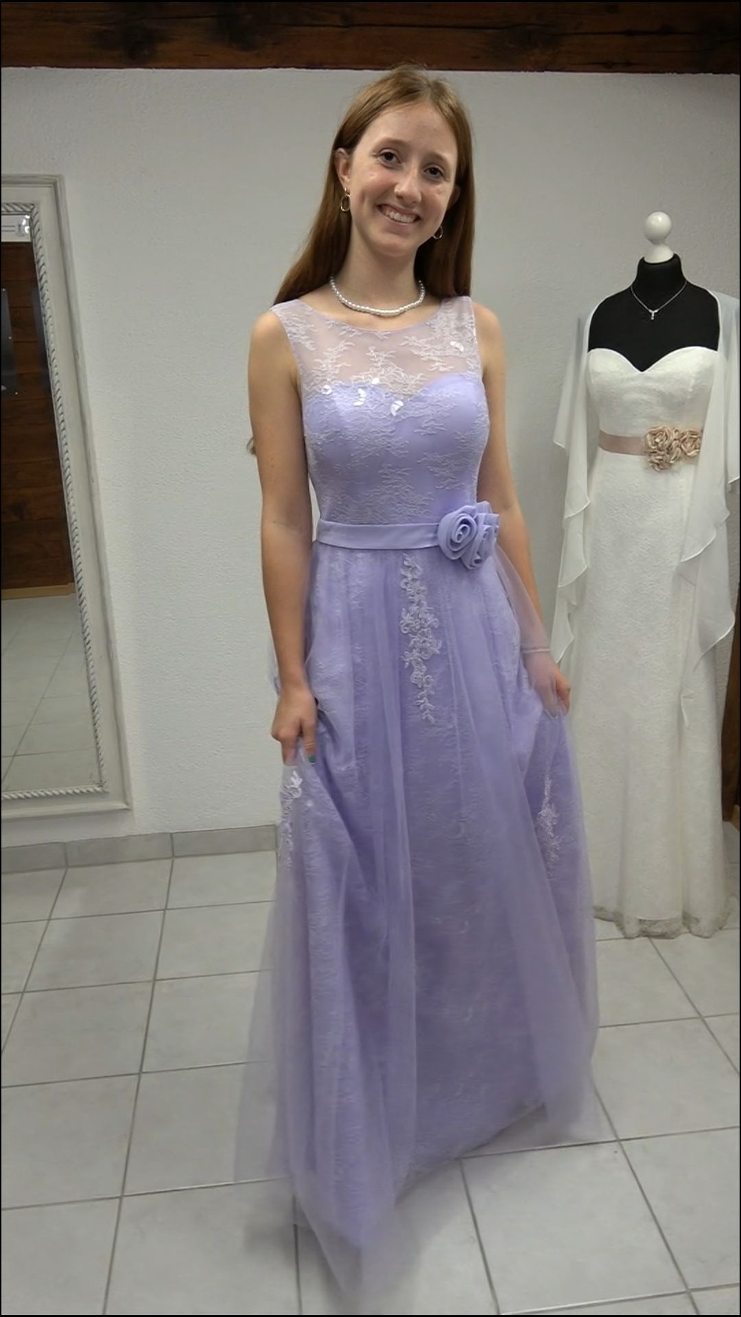 Eine Frau in einem lila Kleid steht vor einer Schaufensterpuppe.