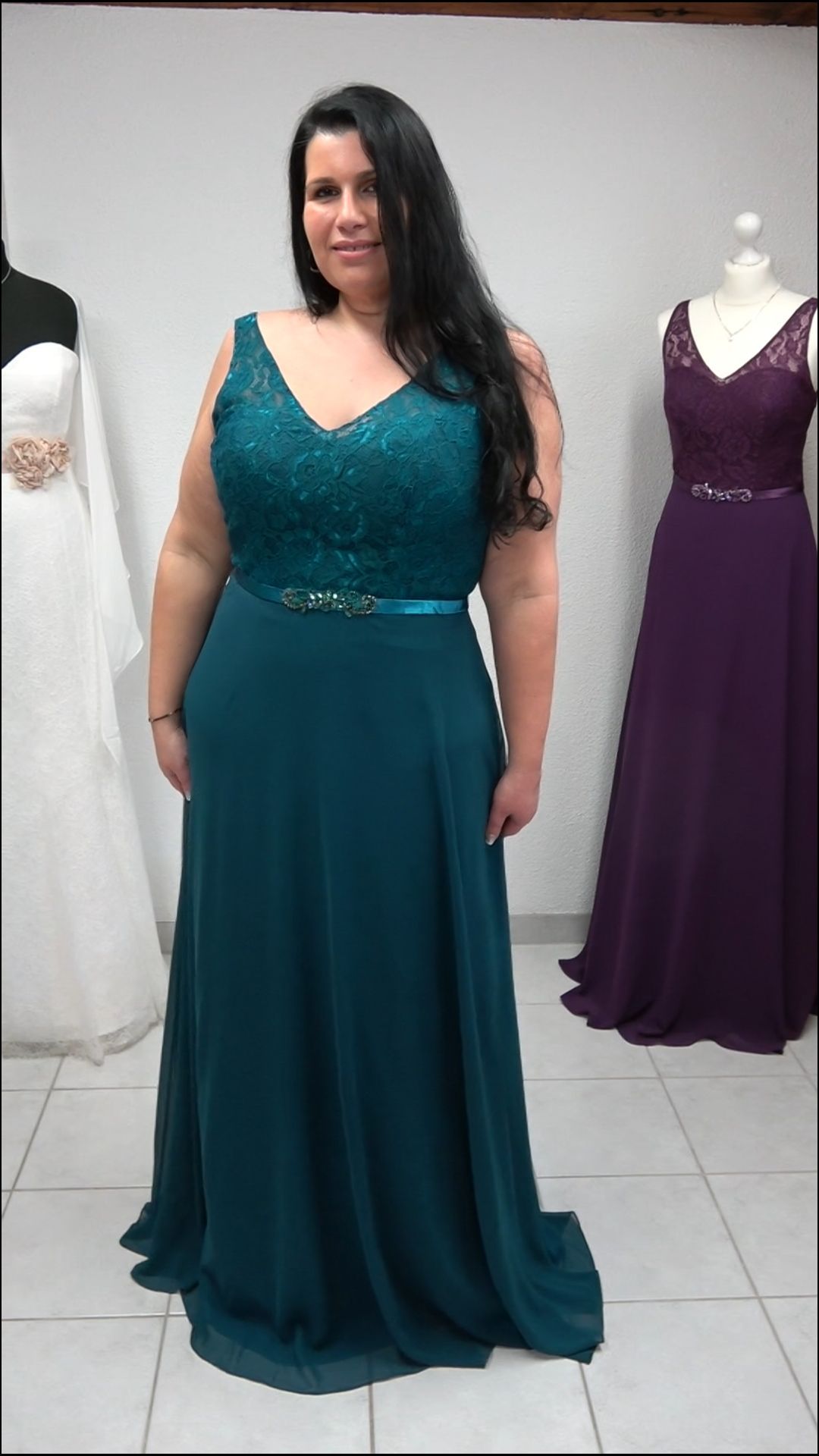 Eine Frau in einem langen grünen Kleid steht vor einer Schaufensterpuppe.