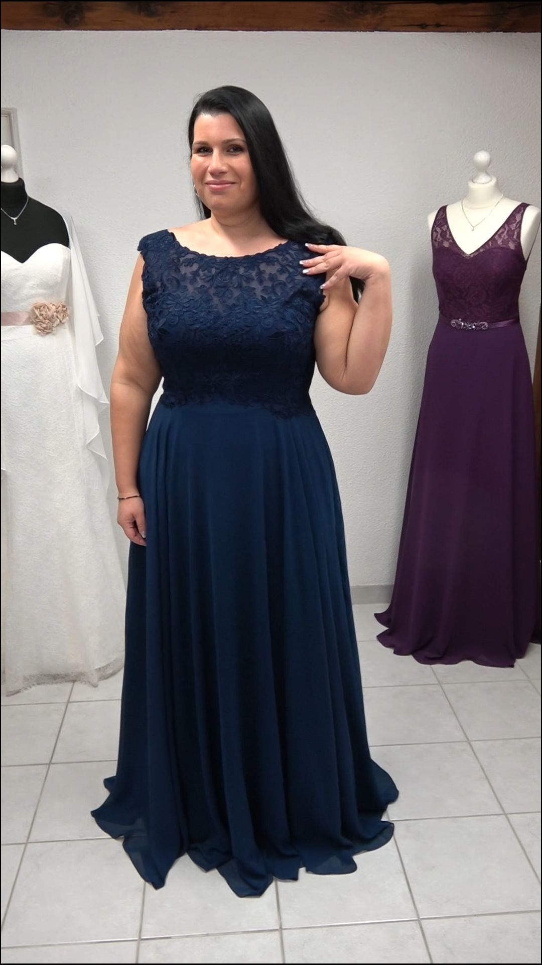 Eine Frau in einem blauen Kleid steht vor einer Schaufensterpuppe.