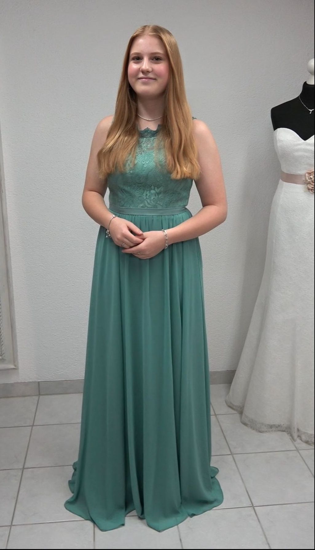 Eine Frau in einem grünen Kleid steht vor einem weißen Kleid.