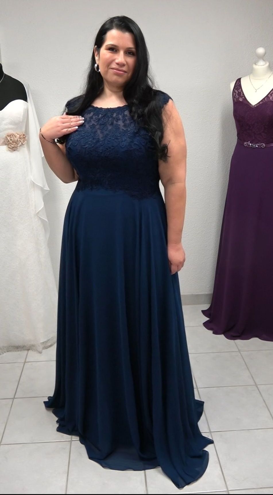 Eine Frau in einem blauen Kleid steht vor einer Schaufensterpuppe.